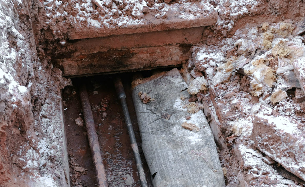 Crash, burst pipes and leaking water under the earth. Excavated pipes in the winter.